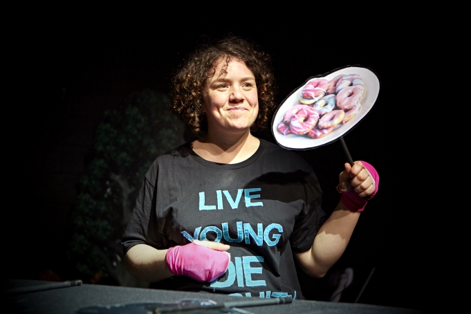 Image of Jess Thom holding a plate of doughnut. Photograph: James Lyndsay